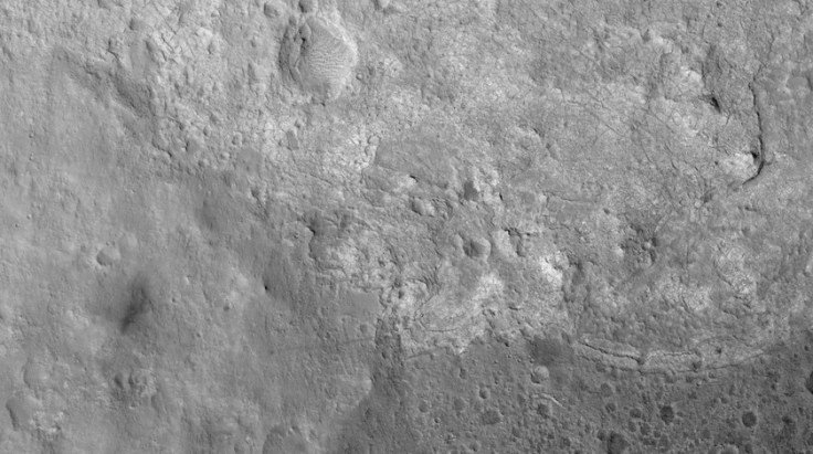 High resolution image of the surface of Mars that Curiosity has crossed. This was taken by the HiRise satellite orbiting Mars. The tracks of the rover are visible and the rover is barely visible in the areas of the light-toned rock. Image credit: NASA/JPL/UA