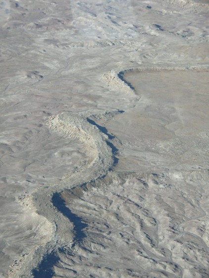 An oblique aerial photograph of a carbonate-cemented, sinuous inverted paleochannel segment located approximately 11 kilometers southwest of Green River, Utah.