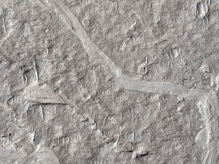 HiRise satelite image of the surface of Mars showing small sand dunes covering an ancient landscape that probably once has a valley of some sort. Maybe a river. Image: NASA/JPL/University of Arizona